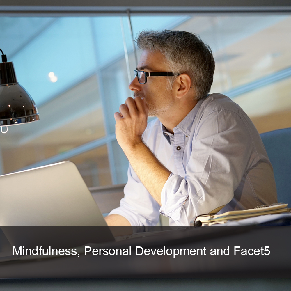 Male worker, sat a desk, takes time to think about personal development.